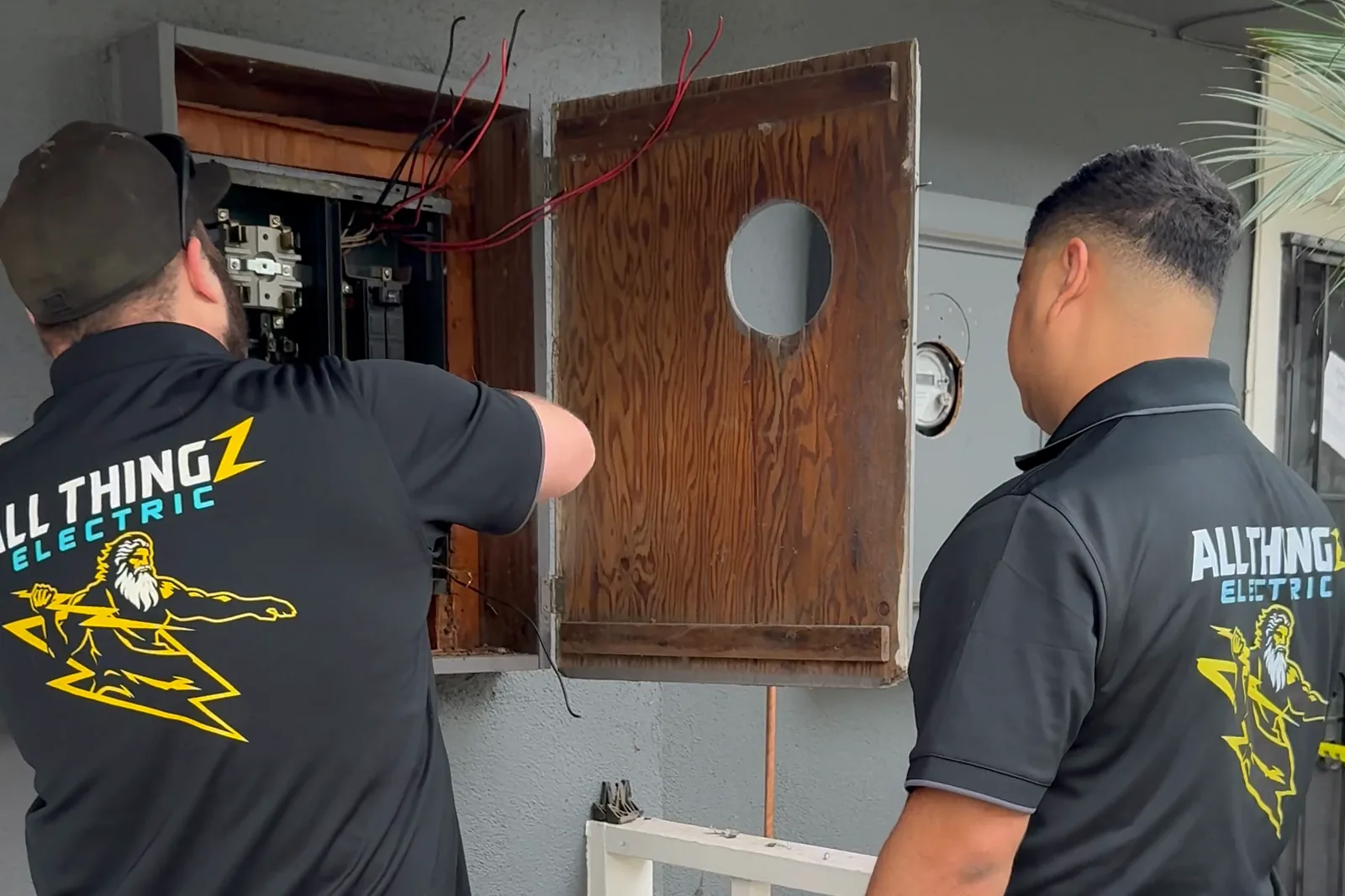 Two Panel Pros technicians replacing an open electrical panel on a community building in Orange County
