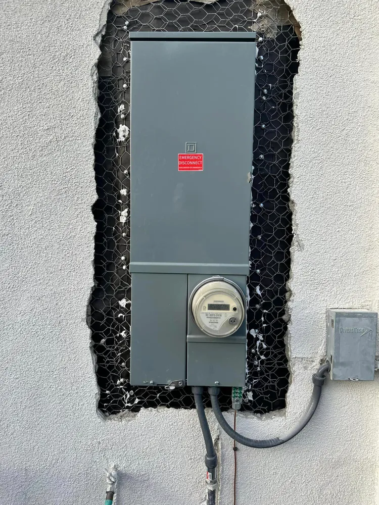 A licensed electrician working inside an open residential electrical panel during a service upgrade